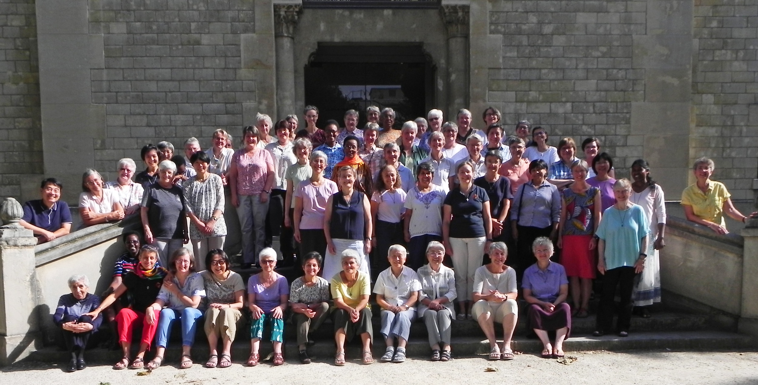 Groupe de sœurs souriantes devant un bâtiment religieux